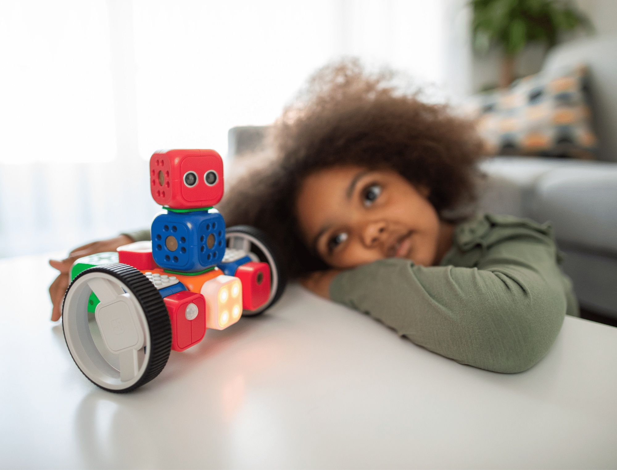 A young black child looks at a STEAM toy on a white desk. Explore Britt Hawthorne’s anti-racist gifts for kids. Photo: Robo Wunderkind